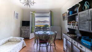 Una habitación con una mesa de comedor, sillas, un televisor, un sofá y vistas a montañas a través de una puerta.