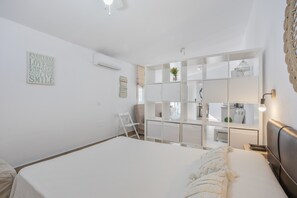 Un dormitorio con una cama grande, una silla, un escritorio y un estante con una planta.