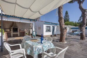 Un patio al aire libre con una mesa, sillas, una parrilla y una hamaca.