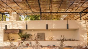 An outdoor dining area with a long table set for a meal, a bar sign, and potted plants.