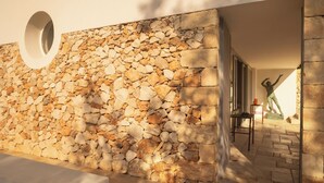 A stone wall with a circular window and a statue of a person.