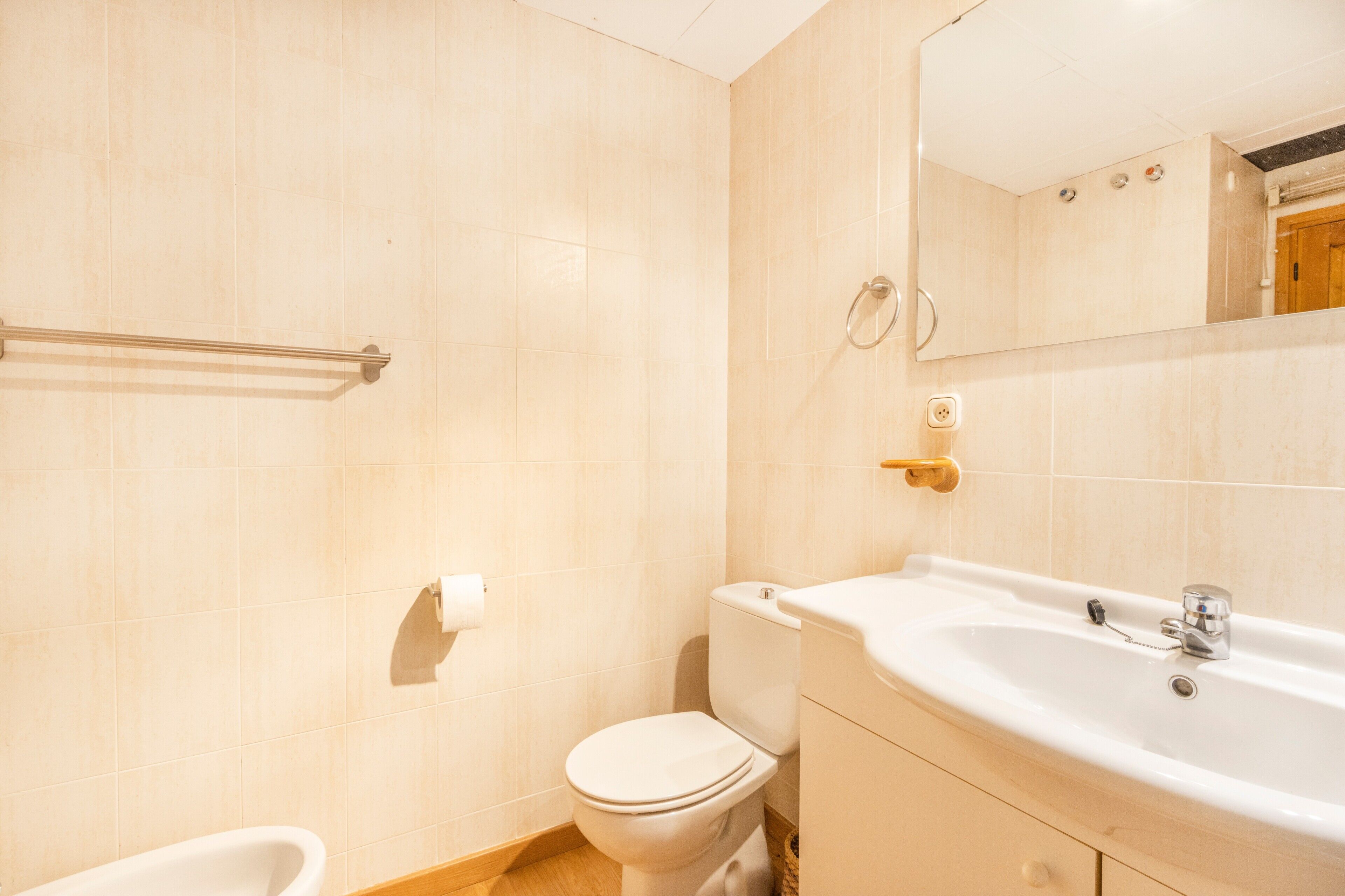Un baño con inodoro, lavamanos y espejo.
