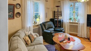 Ein gemütliches Wohnzimmer mit einer Couch, einem schwarzen Ledersessel, einem Holztisch und einer Heizung.