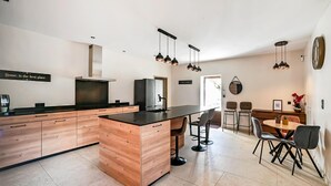 A modern kitchen with a central island, bar stools, a dining table with chairs, and pendant lighting. - Awesome home in Orsan (Orsan)