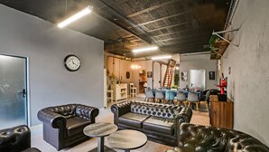 A modern, well-lit room with leather sofas, a round table, and a dining area with blue chairs and a white tablecloth. - Awesome home in Orsan (Orsan)