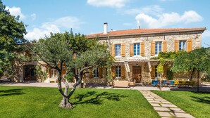 A stone building with a tiled roof, a paved courtyard, and outdoor seating. - Awesome home in Orsan (Orsan)