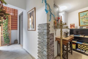 A room with a brick wall, a wooden table, a bookshelf, and a painting.