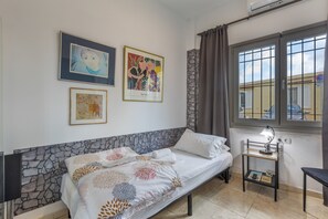 A bedroom with a bed, a nightstand, a window with curtains, and wall art.
