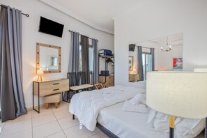 Une chambre d’hôtel comprenant un lit, un bureau avec une chaise, un téléviseur fixé au mur et un miroir.