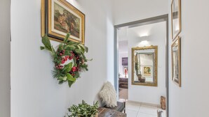 Un couloir avec un banc en bois, une plante en pot, une couronne et un miroir.