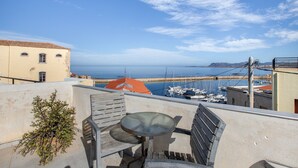 A balcony with a table and chairs, overlooking a marina with boats and a clear sky.