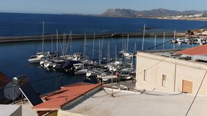 Un puerto deportivo con barcos amarrados, cielo despejado y montañas al fondo.
