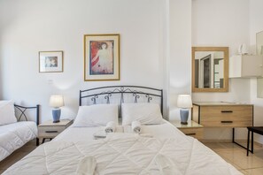 Une chambre d’hôtel comprenant un lit, deux tables de chevet avec des lampes, une commode, un miroir et deux œuvres d’art encadrées accrochées au mur.