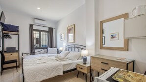 Un dormitorio con cama, mesitas de noche, escritorio, silla, armario y espejo.