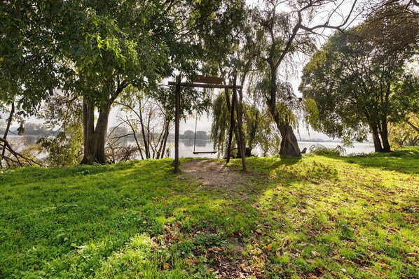 A park with a swing set, trees, and a lake.
