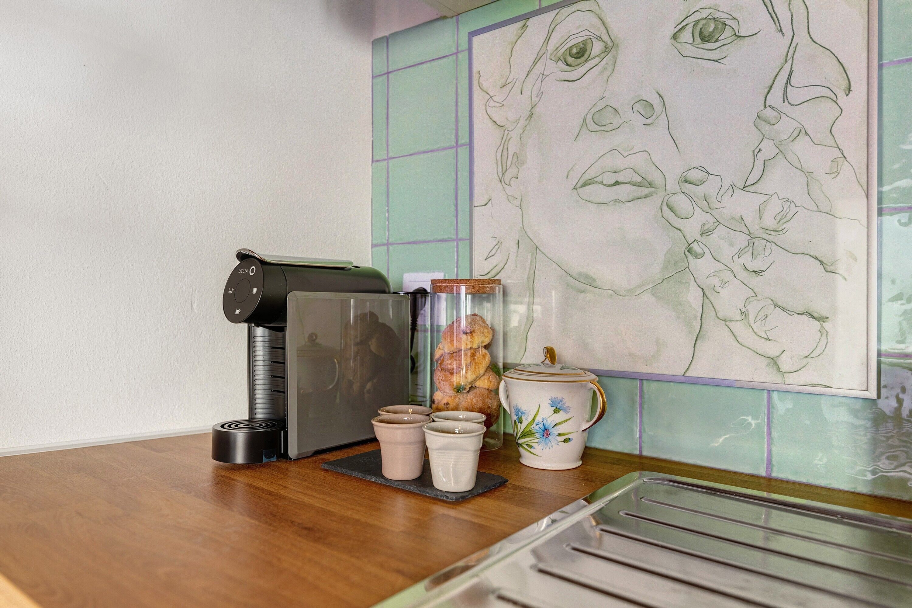 A kitchen counter with a coffee maker, a jar of cookies, and a teapot.
