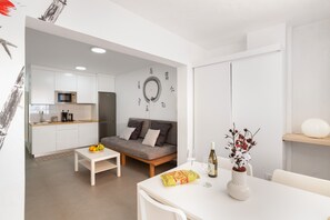 Un espace de vie moderne comprenant une cuisine, un canapé, une table à manger et un mur décoratif.