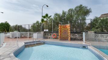 A swimming pool with a tiled deck, a lifebuoy, and a decorative wall.