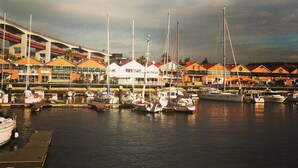 A marina with boats docked, a white tent, and buildings with orange roofs.
