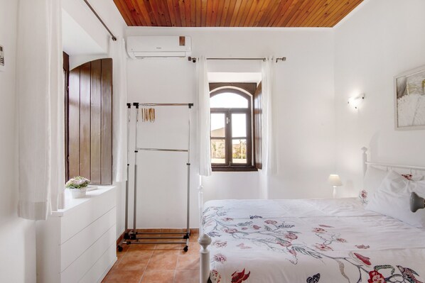 A bedroom with a bed, a window, a door, and a white dresser.