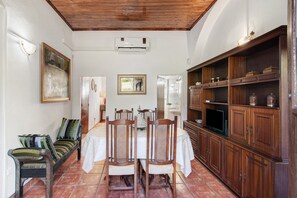 Un espace repas comprenant une table en bois, des chaises, un banc et un meuble avec des étagères.