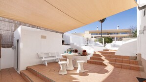 A patio area with a white bench, a round table, and a set of stairs leading to a building. - Holiday Home 'Solar Da Rosa' with Private Pool, Private Terrace and Wi-Fi (Boliqueime)