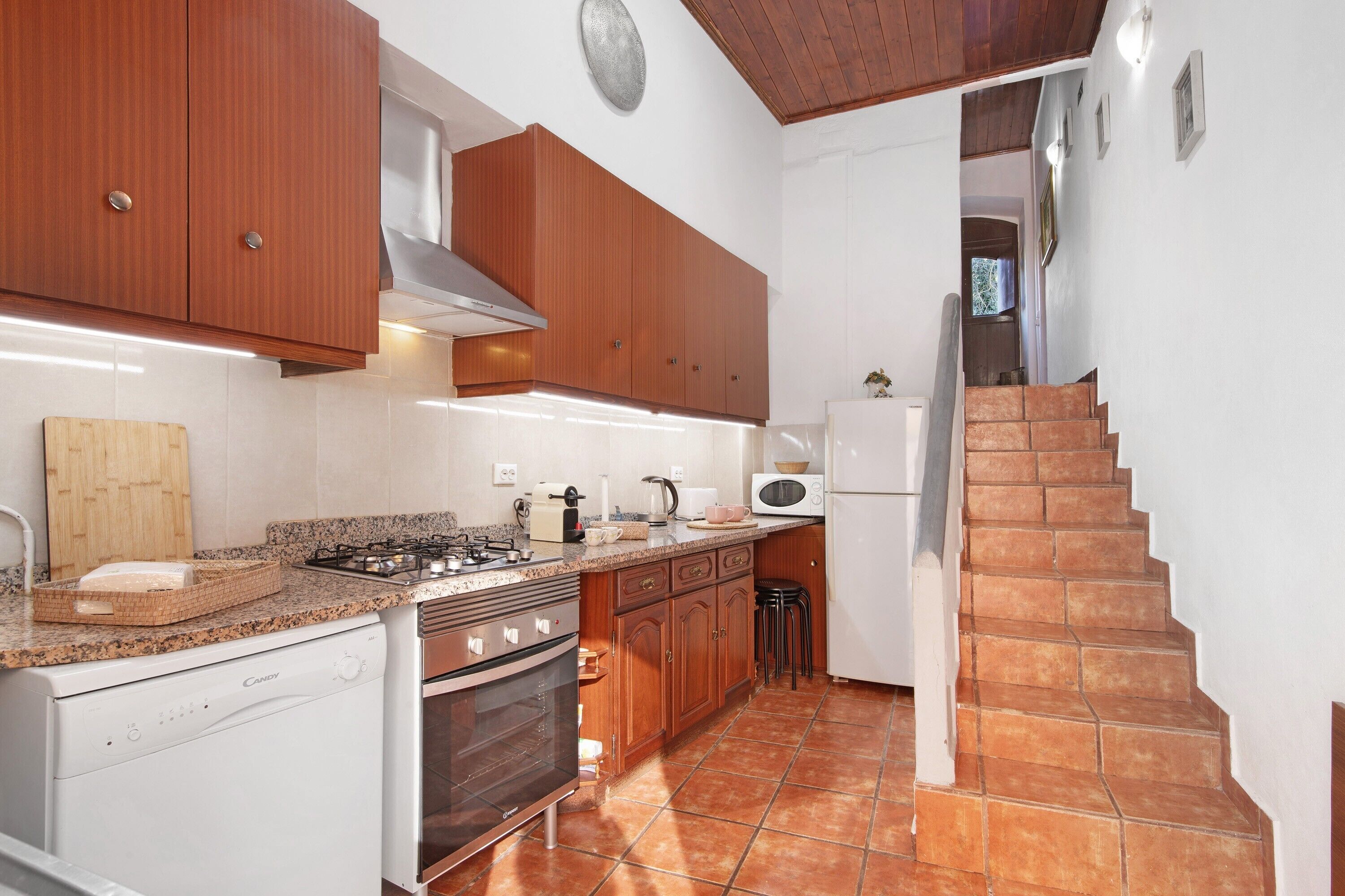 Una cocina con armarios de madera, estufa, microondas y refrigerador.