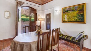 A dining area with a round table, chairs, a bench, a lamp, and a painting on the wall. - Holiday Home 'Solar Da Rosa' with Private Pool, Private Terrace and Wi-Fi (Boliqueime)