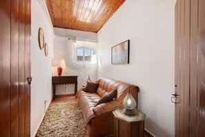 Une pièce avec un canapé en cuir, un plancher en bois, un tapis, une lampe et une fenêtre donnant sur un beau paysage.