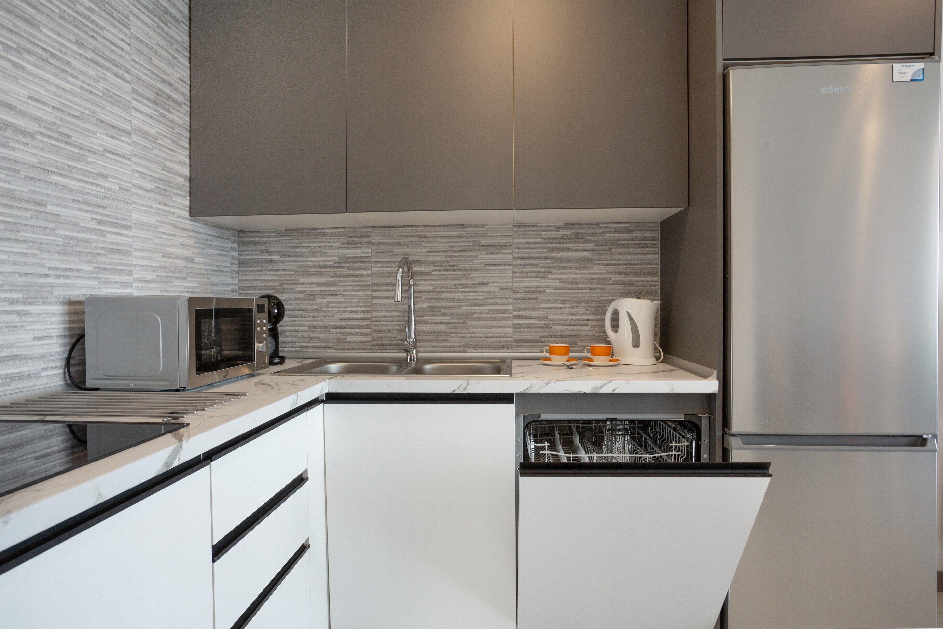 A modern kitchen with a built-in microwave, dishwasher, and stainless steel refrigerator.