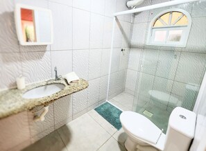 Un bagno con lavabo in granito, WC bianco e cabina doccia in vetro.