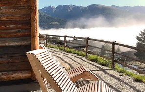Eine Holzterrasse mit einer Bank und Blick auf die Berge.