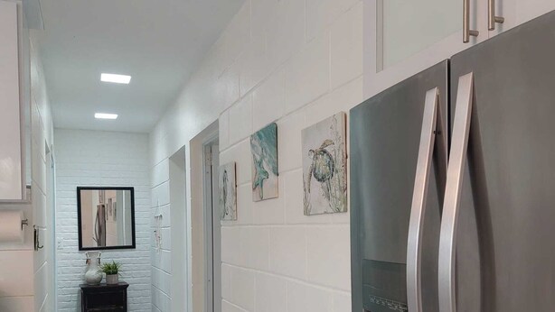 Una cocina con paredes de ladrillo blanco, electrodomésticos de acero inoxidable y cuadros decorativos.
