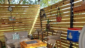 Un patio al aire libre con cerramiento de madera, una bañera de hidromasaje, una mesa con sillas y un cartel que indica que no hay horario de atención.