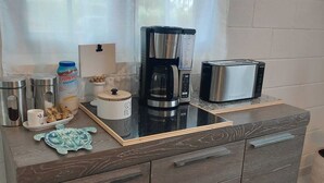 Una kitchenette equipada con cafetera, tostadora y recipientes de almacenamiento.