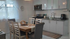 Una cocina moderna con gabinetes blancos, microondas y una mesa de comedor con sillas.