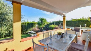 Un patio al aire libre con mesa y sillas, una mesita auxiliar y una planta en maceta.