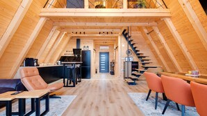 Un vaste loft doté d’un haut plafond, de poutres apparentes, d’un coin cuisine, d’un espace repas et d’un escalier.