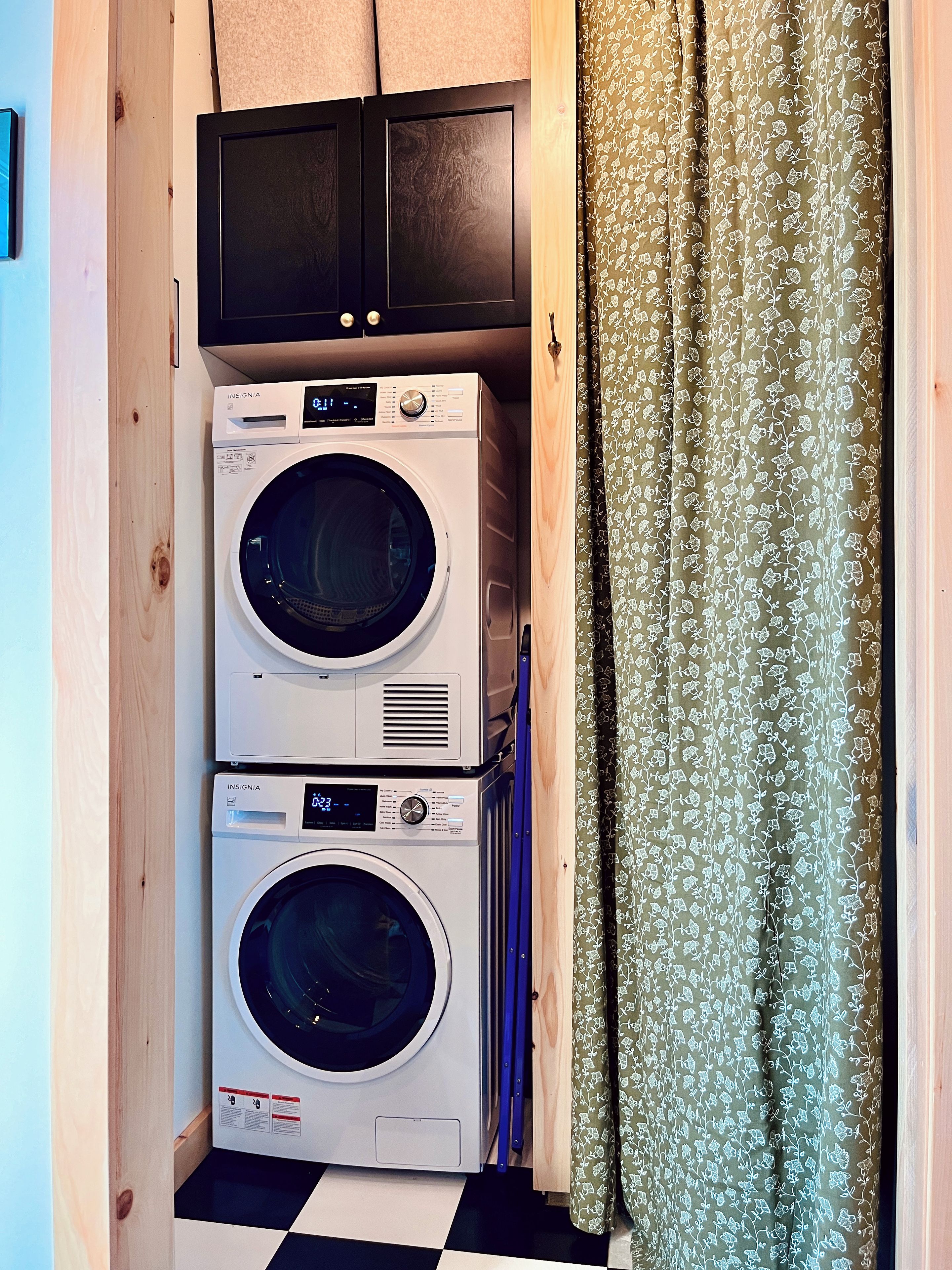 A laundry area with two stacked washing machines and a microwave above them.