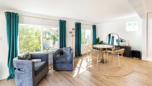 A spacious living area with a sofa, a dining table with chairs, and large windows with curtains. - Mesa Retreat Quiet, Stylish Desert Escape + Golf (Mesa)
