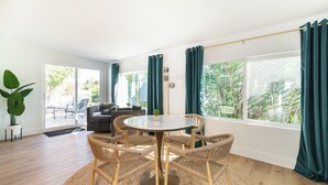 A spacious room with a round table and chairs, large windows with curtains, a sofa, and a potted plant. - Mesa Retreat Quiet, Stylish Desert Escape + Golf (Mesa)