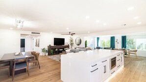 A spacious living area with a large island, wooden flooring, and a modern entertainment unit. - Mesa Retreat Quiet, Stylish Desert Escape + Golf (Mesa)