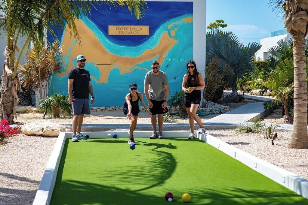 Une partie de croquet se déroule sur un terrain verdoyant, avec une fresque en arrière-plan.