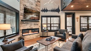 Una sala de estar moderna con chimenea de piedra, asientos cómodos y un ventanal grande.