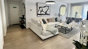 Un salón moderno con un sofá blanco, una mesa de centro y un cuadro en la pared.