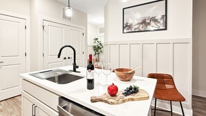 Une cuisine moderne dotée d’un îlot central, de meubles blancs, d’un robinet noir et de luminaires suspendus.