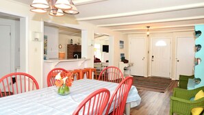 Comedor con una mesa dispuesta para seis personas, rodeada de sillas rojas, un espejo sobre la mesa y una lámpara de candelabro.