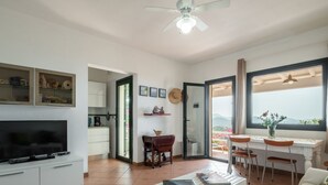 Ein modernes Wohnzimmer mit einem Flachbildfernseher, einem Essbereich mit Tisch und Stühlen sowie ein Balkon mit Aussicht.