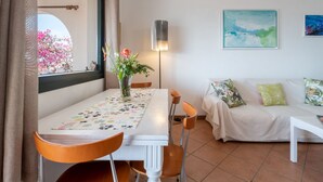 Ein Essbereich mit Tisch, Stühlen, einer Blumenvase, einer Couch und einem Bild an der Wand.