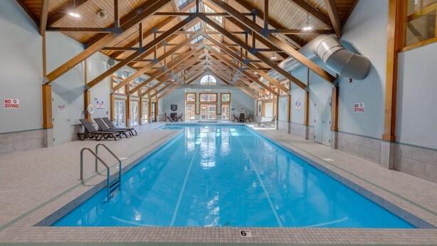 Una piscina interior con un alto techo de madera y amplias ventanas de vidrio.
